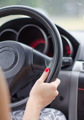 Female driver's hands on a steering wheel of a car